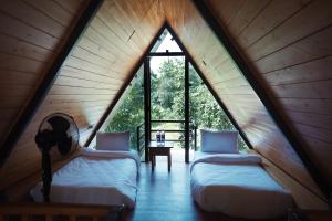 two beds in a room with a large window at LA SELVA Resort, Pench National Park in Khawāsa