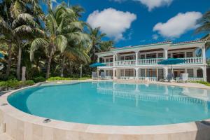 a large swimming pool in front of a house with palm trees at Coral Bay Villas in San Pedro