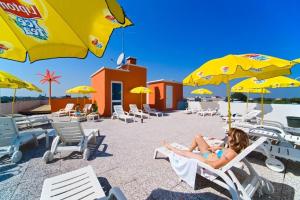 una mujer sentada en sillas bajo sombrillas en una playa en Hotel Di Giovanni en Bibione