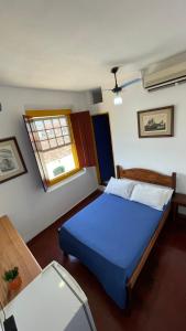 um quarto com uma cama azul e uma janela em Pousada Aquarium Centro Histórico em Paraty