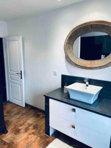 ein Bad mit einem Waschbecken und einem Wandspiegel in der Unterkunft Maison climatisée avec stationnement et wifi in Bram