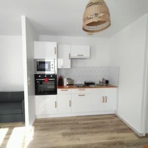 kuchnia z białymi szafkami i czarnym sprzętem AGD w obiekcie Spacieux studio dans résidence avec parking privé w mieście Clermont-Ferrand +6 zdjęć