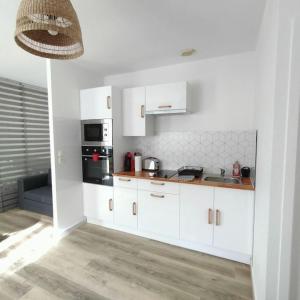 uma cozinha com armários brancos e um forno com placa de fogão em Spacieux studio dans résidence avec parking privé em Clermont-Ferrand