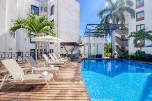 una piscina en un hotel con tumbonas y sombrilla en Seven Boutique 10, en Cancún