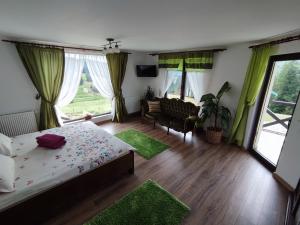 a bedroom with a bed and a couch and windows at Bucovina Sky View in Gura Humorului