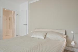 une chambre blanche avec un lit et un miroir dans l'établissement Vienna Central Apartment Siebenbrunnen, à Vienne