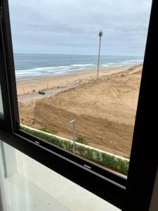 - une vue sur la plage depuis la fenêtre dans l'établissement Superbe appartement Front de mer Prestigia, à Sidi Bouqnadel