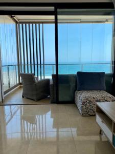 - un salon avec un canapé et une vue sur l'océan dans l'établissement Superbe appartement Front de mer Prestigia, à Sidi Bouqnadel