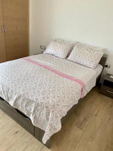 Superbe appartement Front de mer Prestigia في Sidi Bouqnadel: سرير مع لحاف ووسائد وردية وبيضاء