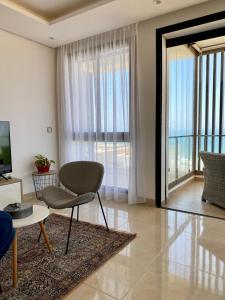 - un salon avec une chaise et une grande fenêtre dans l'établissement Superbe appartement Front de mer Prestigia, à Sidi Bouqnadel