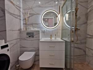 a bathroom with a toilet and a sink and a mirror at Gold Apartment B33 Let's Sea Baltic Park Gąski in Gąski