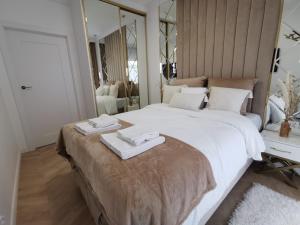 une chambre avec un grand lit avec deux serviettes dessus dans l'établissement Gold Apartment B33 Let's Sea Baltic Park Gąski, à Gąski 82 autres photos