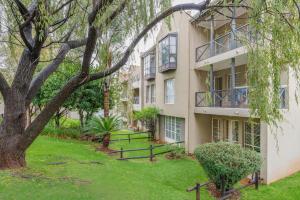 an apartment building with a tree in the yard at Modern 2 bedroom apartment in vibrant Melville 99 in Johannesburg