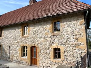 un antiguo edificio de piedra con ventanas y techo marrón en Le gite de Longcochon, en Longcochon