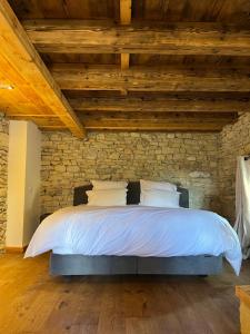 a bedroom with a bed in a stone wall at Le gite de Longcochon in Longcochon