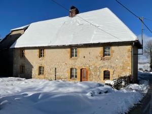 una casa de piedra con nieve en el techo en Le gite de Longcochon, en Longcochon