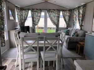 uma sala de estar com uma mesa e cadeiras e um sofá em Delightful 2-bed static set in a peaceful village em Gilcrux