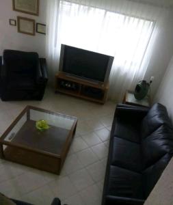 uma sala de estar com uma televisão, um sofá e uma mesa de centro em Delfin bnb em Cruz de Huanacaxtle