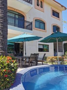 a house with a swimming pool with two umbrellas at Delfin bnb in Cruz de Huanacaxtle