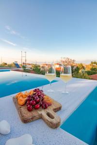 a table with two glasses of wine and some vegetables at Georgianna's suite with private pool , 'blank suite' in Kharokopión