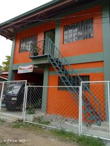 a orange building with a staircase on the side of it at Estrelle Orange House - Backpackers Hub in Puerto Princesa City