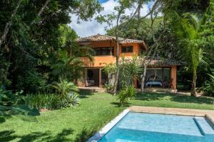 a villa with a swimming pool in front of a house at Casa Laranjeiras, Rio da Barra beach, Trancoso in Trancoso