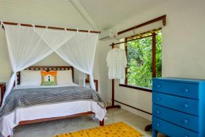 ein Schlafzimmer mit einem Himmelbett und einer blauen Kommode in der Unterkunft Casa Laranjeiras, Rio da Barra beach, Trancoso in Trancoso