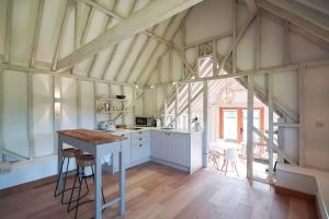 a kitchen with white cabinets and a table in a room at The Cowshed, Tunbridge Wells in Royal Tunbridge Wells