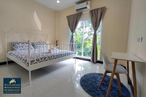 um quarto com uma cama branca e uma janela em MaiKhao Residence em Praia de Mai Khao