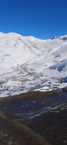 a snowy mountain with a town in the foreground at AliveNino in Xınalıq
