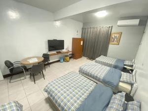 Changhua County的住宿－彰濱伸港民宿，客房设有两张床、一张桌子和电视。