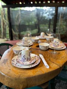 una mesa de madera con platos y tazas y copas de vino en Casa Tropical Playa Grande, en Cuajiniquil