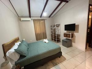 Casa Tropical Playa Grande في Cuajiniquil: غرفة نوم بسرير وتلفزيون بشاشة مسطحة