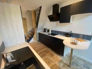 een keuken met zwarte kasten en een wit aanrecht bij Appartement centre-ville de Valognes in Valognes