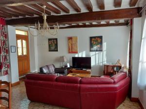 uma sala de estar com um sofá vermelho e uma televisão em Chez Robins em Trie-Château