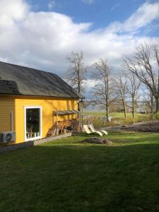 a yellow house with a porch and a yard at Ferienhaus am Vänern mit Seeblick in Mariestad