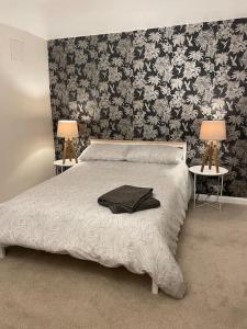 a bedroom with a bed and two tables with lamps at Stylish & Spacious 2 Storey, 3 Bed Apartment in Kent