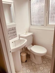 a white bathroom with a toilet and a sink at Stylish & Spacious 2 Storey, 3 Bed Apartment in Kent
