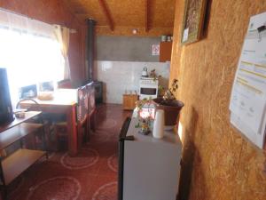 cocina con nevera y mesa en una habitación en Hostal y Cabañas Perla del Lago, en Puerto Guadal