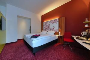 a bedroom with a bed and a desk with a computer at IBB Hotel Ingelheim in Ingelheim am Rhein