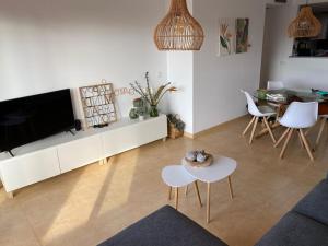 ein Wohnzimmer mit einem TV, einem Tisch und Stühlen in der Unterkunft Apartment Sol Dorado - Mar Menor Golf Resort in Torre-Pacheco