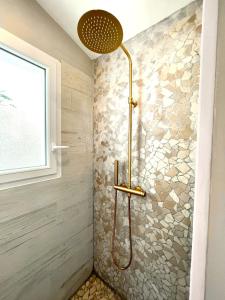 um chuveiro na casa de banho com uma parede de pedra em Studio Piscine Balnéo Chauffée em Sérignan