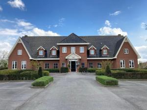 a large red brick house with a driveway at Hotel Swaenenburg in Oostrozebeke