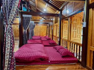 a group of four beds in a wooden room at A Sính Homestay in Ha Giang