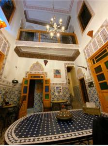 a dining room with a table and a chandelier at Riad lala Drissia in Fez