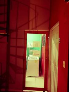 Cette chambre dispose d'un réfrigérateur et d'un mur rouge. dans l'établissement Guest house La Casa del Quetzal, à Mérida