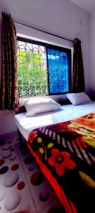 Cama en habitación con ventana y alfombra en Nilam Guest House en Bodh Gaya