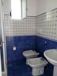 La salle de bains est pourvue de carrelage bleu, de toilettes et d'un lavabo. dans l'établissement Sunshine, à Capri