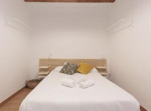 1 dormitorio con 1 cama blanca y 2 toallas en Ndlr 2-4 · Authentic flat in Poble Sec - Paralelo, en Barcelona