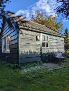 a small wooden cabin with a bench in front of it at Het Duinhuisje in Goedereede